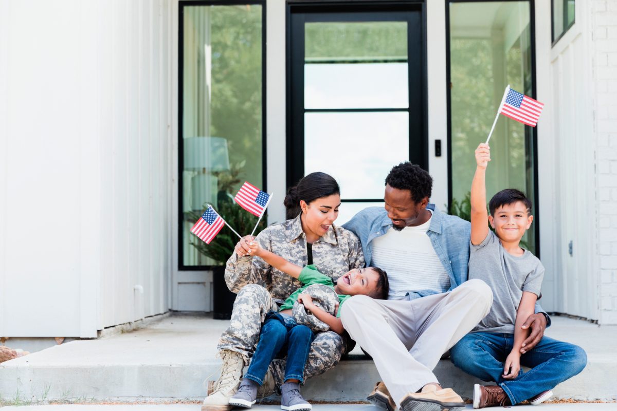 Family enjoying a moment with American flags on their front porch.