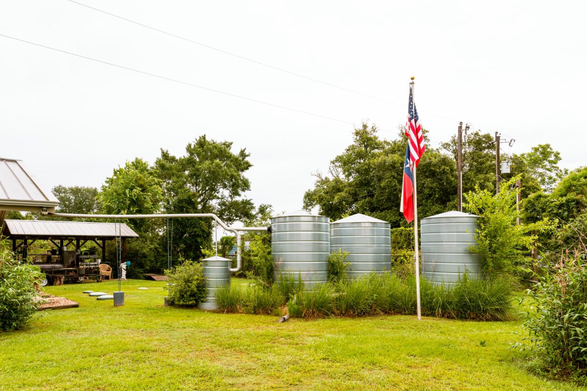 Three large water tanks with American and Confederate flags on a grassy field.