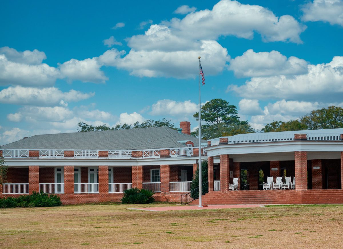 A red brick school building under a blue sky with scattered clouds.