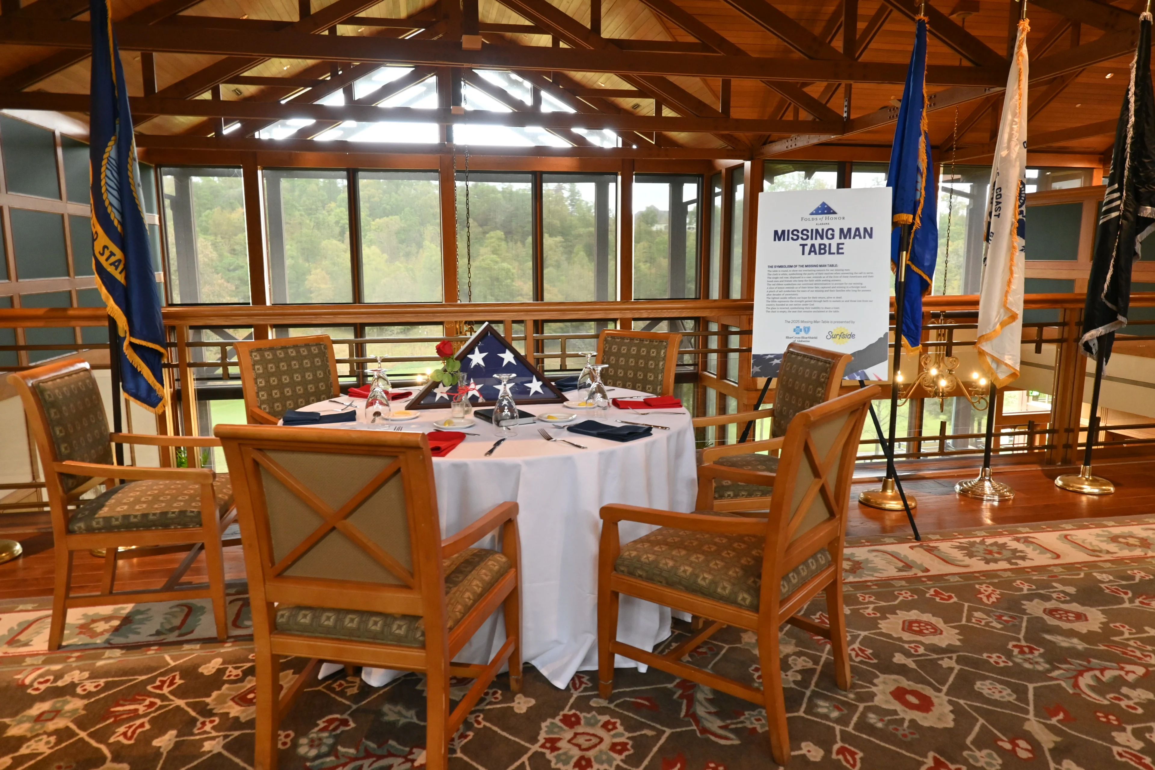 Elegantly set round dining table in a rustic wooden lodge with scenic forest views.